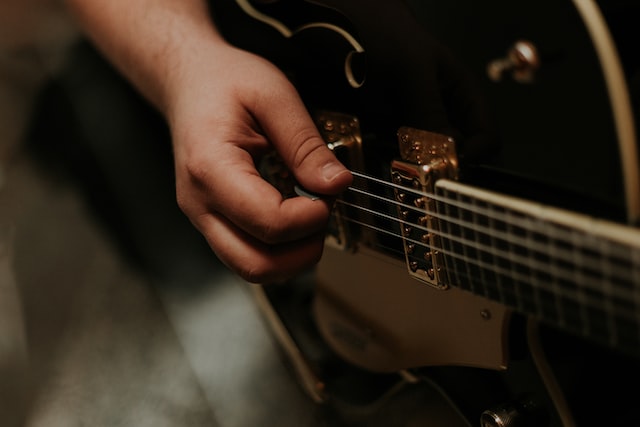 A person picks an electric guitar