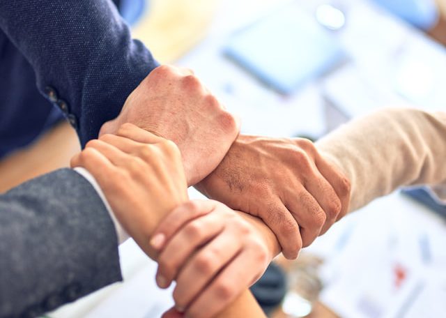 Group of business workers standing with hands together doing symbol at the office