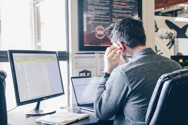 Man listening to music as he works at his desk on a laptop in an urban office