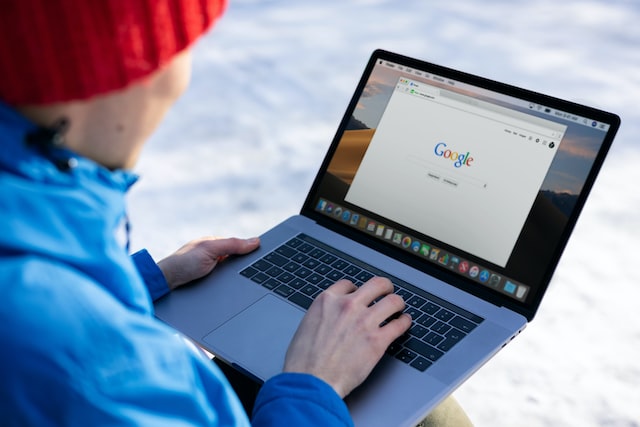 outside and uses Apple MacBook to research Google