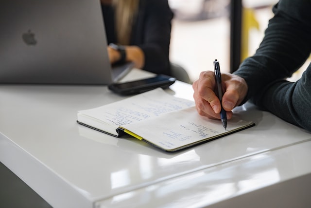 man writes in a notebook