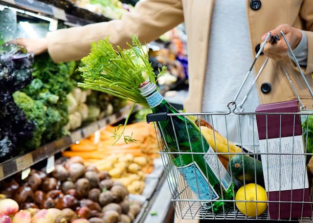 woman-in-white-coat-holding-green-shopping-cart