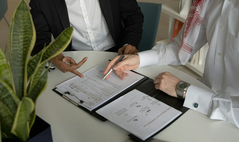 two-men-sitting-at-a-table-with-papers-and-a-pen