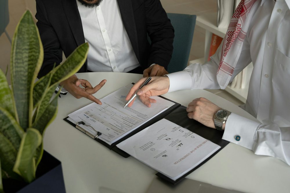 two-men-sitting-at-a-table-with-papers-and-a-pen
